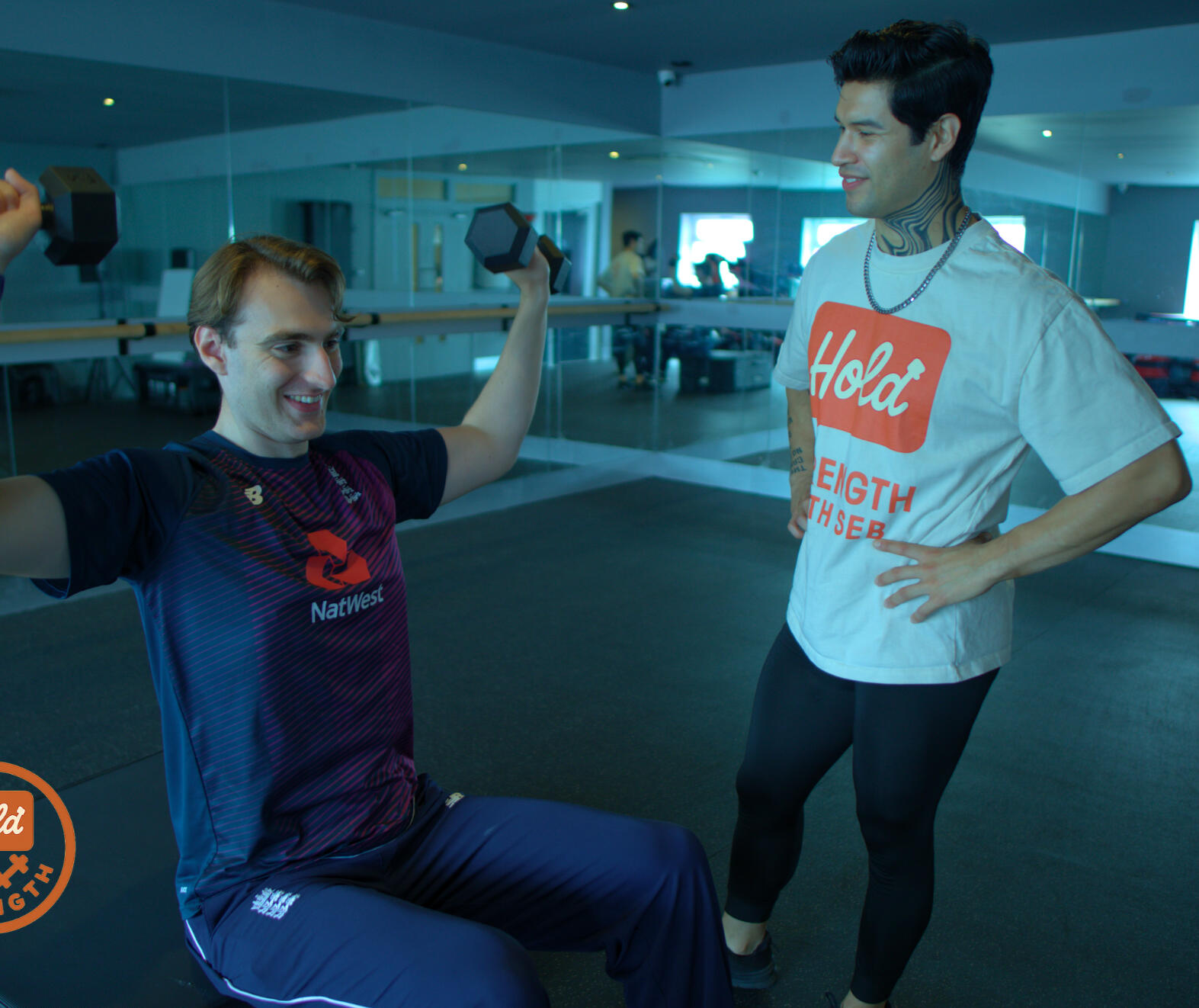 Seb, bilingual personal trainer in London, assisting a male client with shoulder press form for safe and effective strength training.
